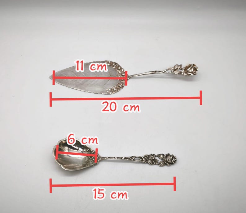 Peut inclure: Deux ustensiles de service argent&eacute;s. Le serveur &agrave; tarte mesure 20 cm de long et 11 cm de large. La cuill&egrave;re mesure 15 cm de long et 6 cm de large. Les deux ont des motifs de roses florales sur les manches.