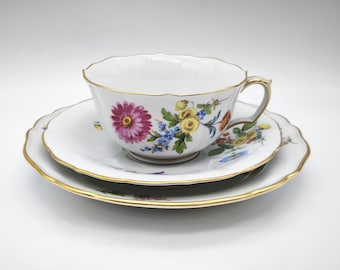 Trío de porcelana antigua de Meissen: juego de taza, plato y platillo, con motivos florales esparcidos pintados a mano y detalles dorados, porcelana antigua alemana.