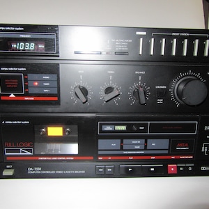 May include: A black Sansui DA-T550 computer-controlled stereo cassette receiver featuring a digital frequency display, preset station buttons, volume and tone control knobs, a cassette deck with full logic controls, and Dolby NR system.