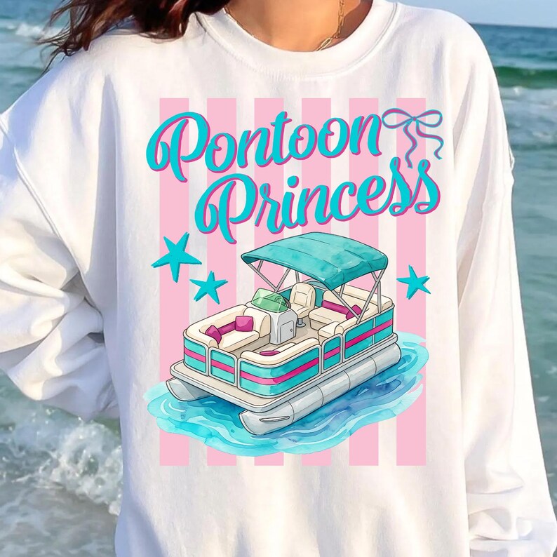 May include: White sweatshirt with a graphic of a pontoon boat and the text "Pontoon Princess" in teal script. The design includes pink stripes and teal stars, creating a fun, nautical theme.