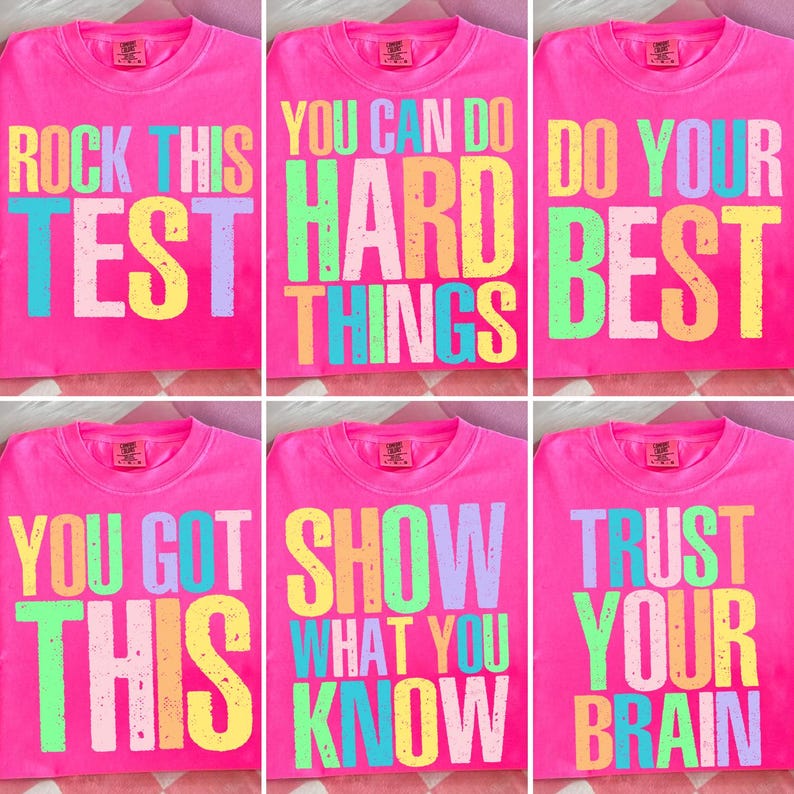 May include: A collection of six pink t-shirts with colorful text. The shirts display phrases like "ROCK THIS TEST", "YOU CAN DO HARD THINGS", and "DO YOUR BEST". Each shirt has a small logo near the neckline.