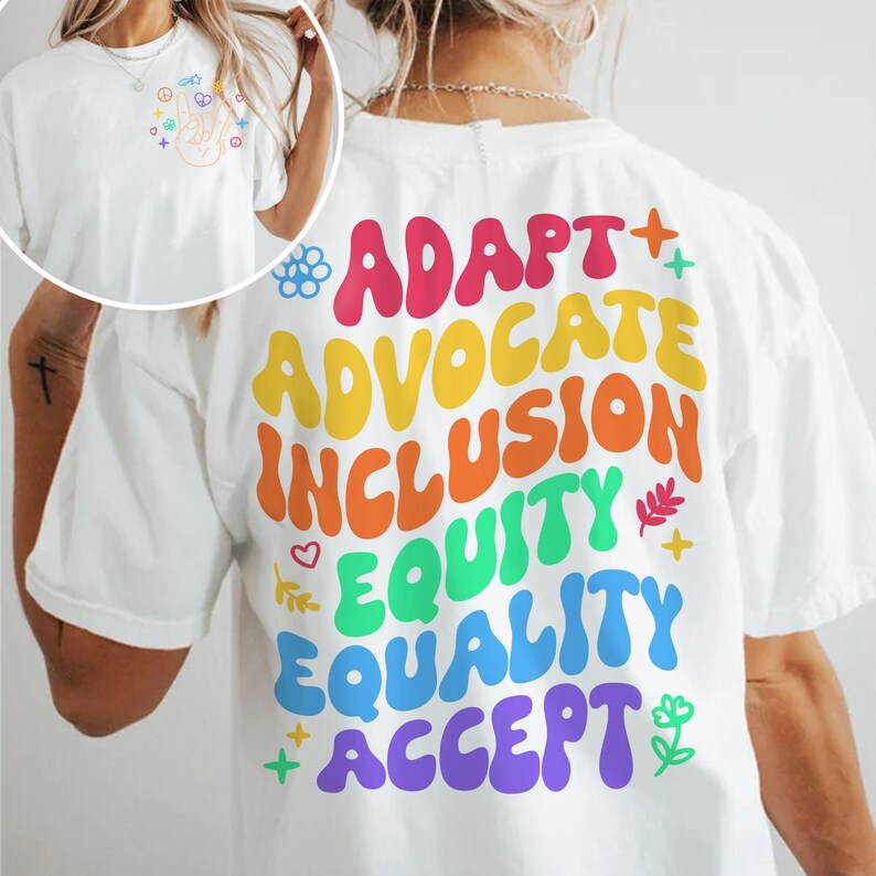 May include: White t-shirt with a rainbow-colored graphic on the back that says "ADAPT + ADVOCATE + INCLUSION + EQUITY + EQUALITY + ACCEPT".
