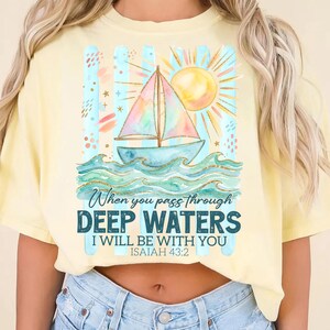K&ouml;nnte beinhalten: Hellgelbes T-Shirt mit einem Segelboot-Motiv. Das Design zeigt ein Segelboot auf blauen Wellen, eine Sonne und den Text "When you pass through DEEP WATERS I WILL BE WITH YOU ISAIAH 43:2". Das T-Shirt hat eine lockere Passform.
