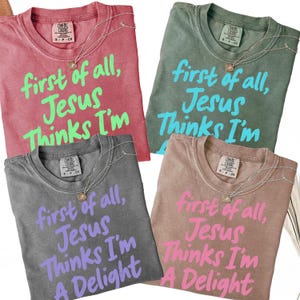 May include: Four Comfort Colors t-shirts in various colors: red, green, grey, and tan. Each shirt features the text "first of all, Jesus Thinks I'm" in a contrasting color. A Delight is added to the grey and tan shirts. Each shirt has a necklace.