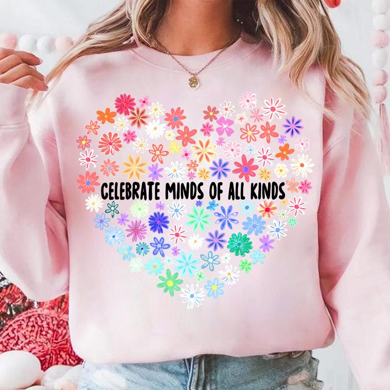 May include: Pink sweatshirt with a rainbow heart made of flowers and the text "Celebrate Minds of All Kinds".