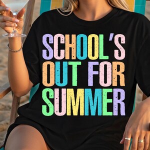 May include: Black t-shirt with the text "SCHOOL'S OUT FOR SUMMER" in colorful, gradient lettering. The shirt is a casual summer garment, perfect for the end of the school year.