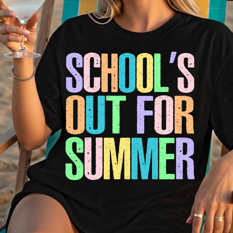 May include: Black t-shirt with the text "SCHOOL'S OUT FOR SUMMER" in colorful, gradient lettering. The shirt is a casual summer garment, perfect for the end of the school year.