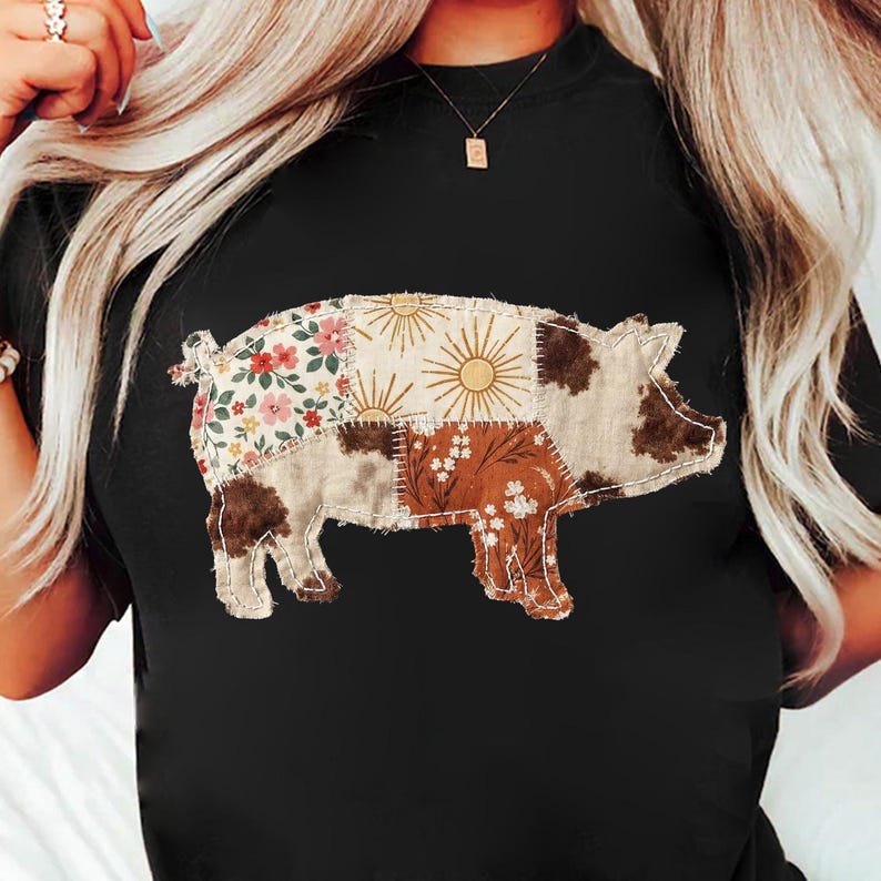 May include: Black t-shirt featuring a patchwork pig design. The pig is composed of various fabric patterns, including floral, sunburst, and cowhide prints. The design is centered on the shirt, creating a rustic and country-inspired aesthetic.