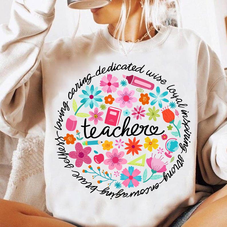 May include: White sweatshirt with a colorful circle design featuring the word "teacher" surrounded by flowers, school supplies, and the words "smart - loving - caring - dedicated - wise - loyal - inspiring - brave - strong - kind -  true".