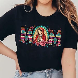 May include: Black t-shirt with the word "MOM" in a colorful, patterned design. The letter shapes are filled with floral and animal print patterns. A central illustration depicts a woman in a red robe, surrounded by roses.