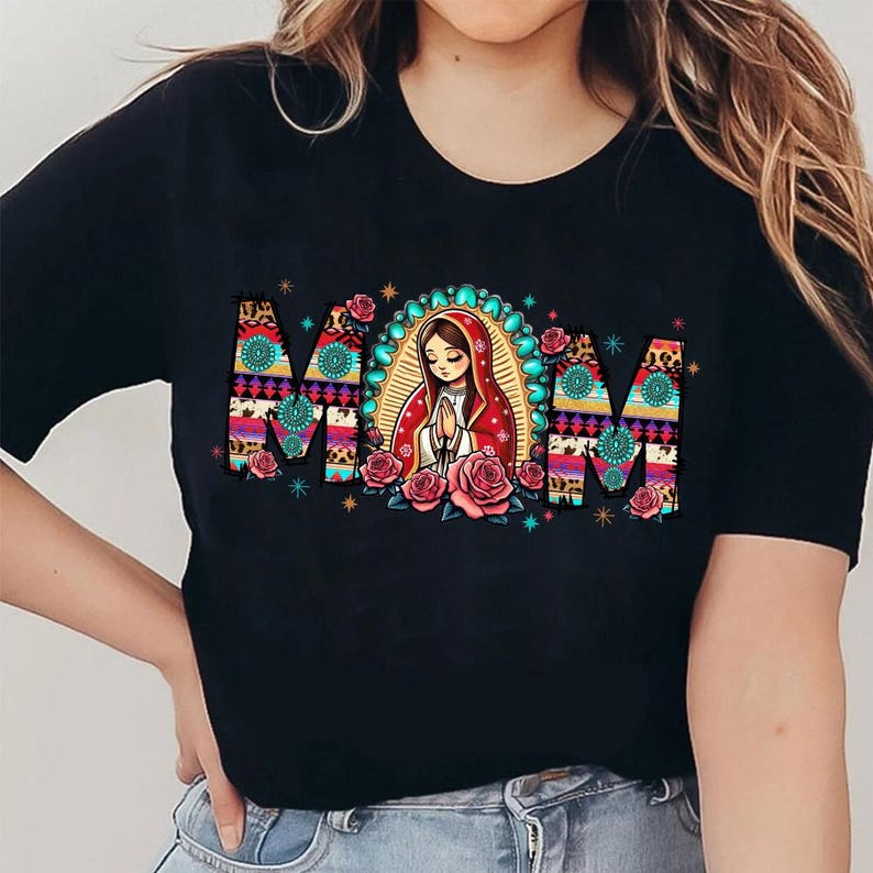 May include: Black t-shirt with the word "MOM" in a colorful, patterned design. The letter shapes are filled with floral and animal print patterns. A central illustration depicts a woman in a red robe, surrounded by roses.