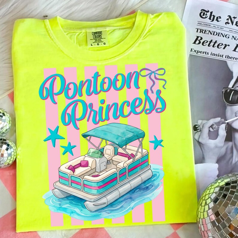 May include: A neon yellow t-shirt with a graphic that says "Pontoon Princess". The graphic features a cartoon pontoon boat with a teal canopy, pink and teal accents, and blue stars. The shirt has a Comfort Colors tag.