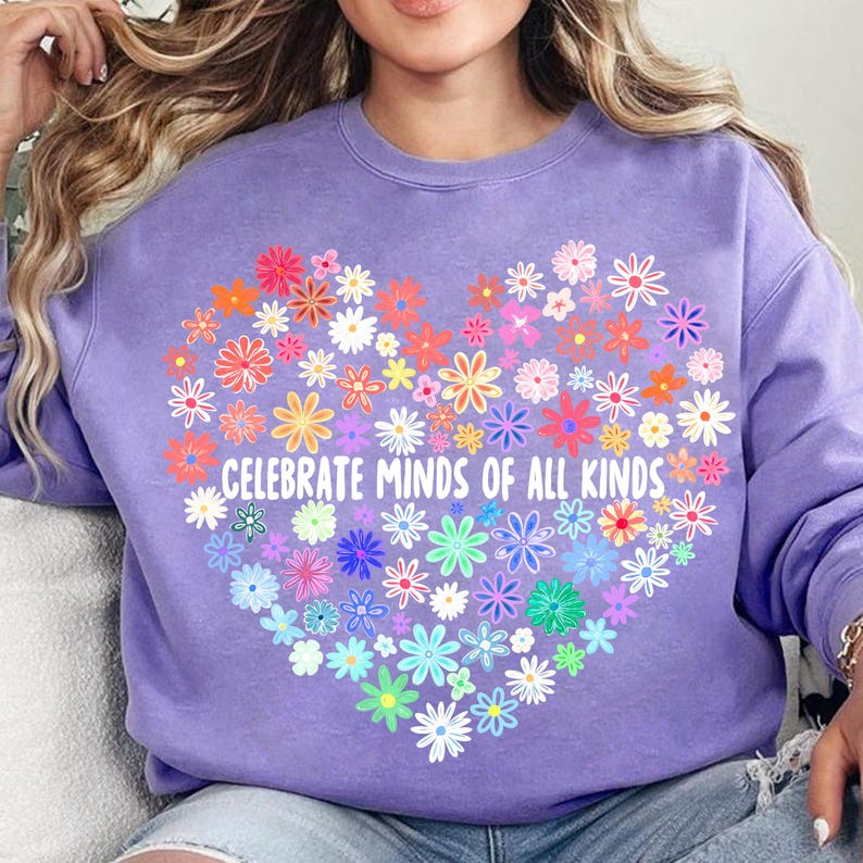 May include: Purple sweatshirt with a heart-shaped design made of colorful flowers. The text "Celebrate Minds of All Kinds" is printed inside the heart.