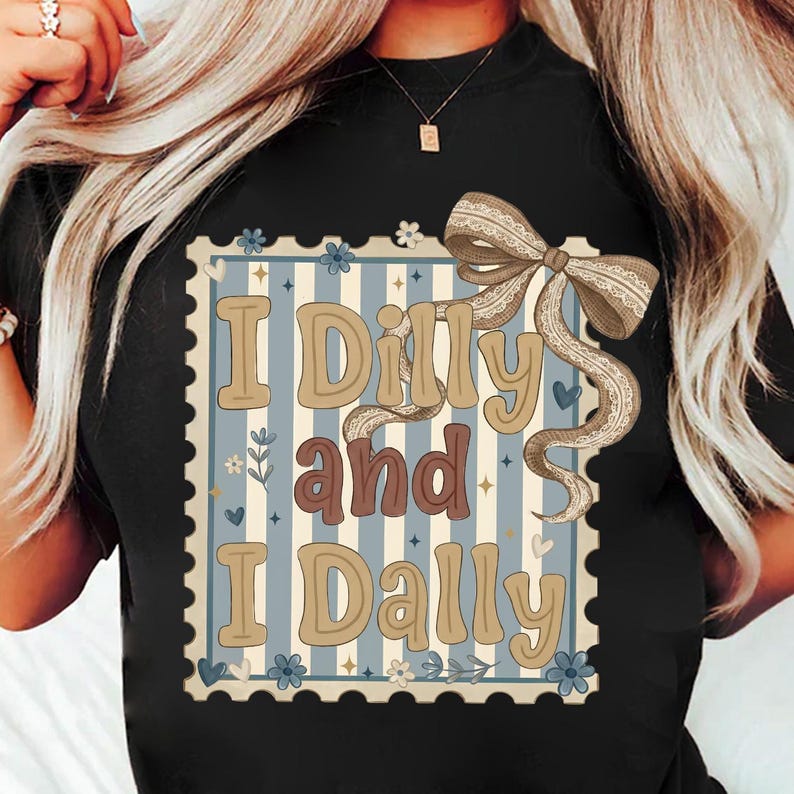 May include: Black t-shirt featuring a decorative design with the text "I Dilly and I Dally." The design includes a light blue and white striped background, floral accents, and a large bow.