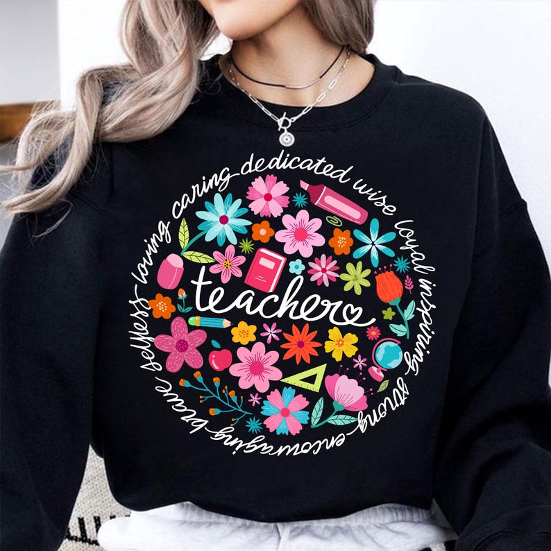 May include: Black sweatshirt with a colorful floral design and the text "caring, dedicated, wise, loyal, inspiring, strong, selfless, loving, brave, amazing, teacher".
