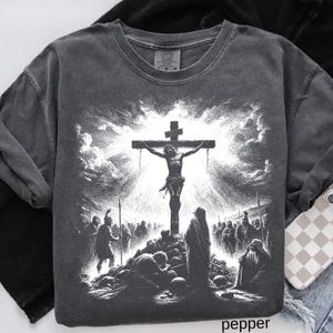 May include: Pepper-colored crew neck sweatshirt featuring a detailed black and white graphic of the crucifixion of Jesus. The design includes a cross, figures, and a dramatic sky. The word "pepper" is printed at the bottom.