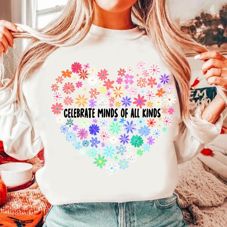 May include: White sweatshirt with a rainbow heart made of flowers and the text "Celebrate Minds of All Kinds".