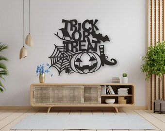 Puede incluir: Arte de pared de Halloween de metal negro con las palabras "TRICK OR TREAT", una calabaza, una telaraña, un murciélago y una bota de bruja. La pieza decorativa está montada en una pared blanca sobre un mueble de madera.