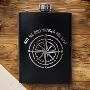 May include: Black stainless steel flask with a compass design and the text "Not all who wander are lost".