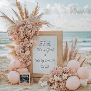 Könnte beinhalten: Ein Schild aus Holz mit dem Text "Our beach days just got sweeter. It's a girl. Baby Smith arrives Oct 2025." Das Schild ist mit rosa Blumen und Pampasgras verziert.