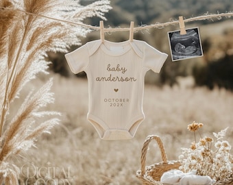 May include: A white baby onesie with the text "baby anderson" and "OCTOBER 202X" printed on it. The onesie is hanging on a clothesline with a small ultrasound image hanging next to it.