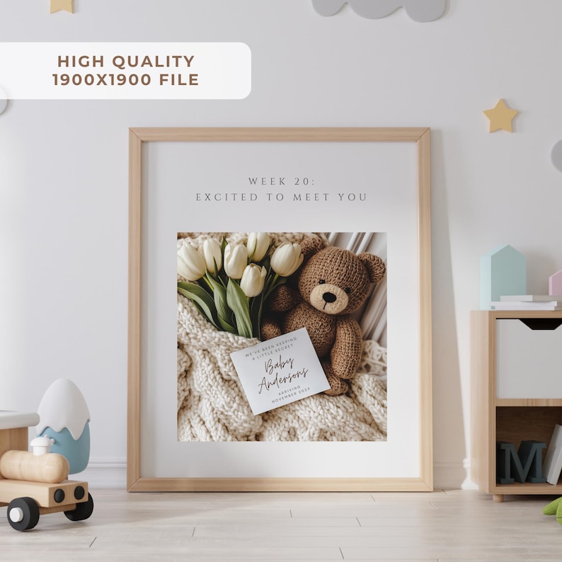 May include: A framed print with a light wood frame. Inside the frame is a photo of a teddy bear, white tulips, and a card that reads "Baby Andersons". The text "Week 20: Excited to Meet You" is at the top. The image is on a white background.