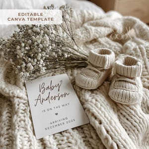 Peut inclure: Une carte d'annonce de naissance de couleur neutre avec le texte "Baby Anderson is on the way, arriving December 2025" est pos&eacute;e sur une couverture en tricot cr&egrave;me. Deux chaussons de b&eacute;b&eacute; en tricot cr&egrave;me sont &agrave; c&ocirc;t&eacute; de la carte. Des fleurs blanches sont en arri&egrave;re-plan.
