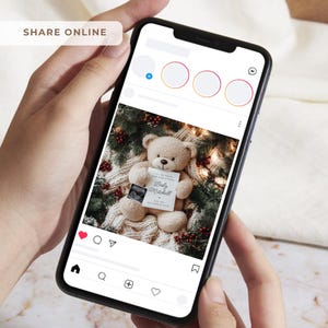 K&ouml;nnte beinhalten: Ein Smartphone zeigt einen Social-Media-Beitrag mit einem Teddyb&auml;ren, der eine Karte mit dem Text "Baby Mitchell" und einem Ultraschallbild h&auml;lt. Der B&auml;r sitzt auf einer gem&uuml;tlichen wei&szlig;en Decke mit festlichem Gr&uuml;n.