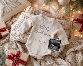 Könnte beinhalten: Ein cremefarbener Baby-Body mit dem Text "Baby Anderson" und "DECEMBER 2025" wird auf einer Strickdecke präsentiert. Ein Ultraschallbild befindet sich neben dem Text. Die Szene umfasst verpackte Geschenke mit roten Bändern und Weihnachtsschmuck.
