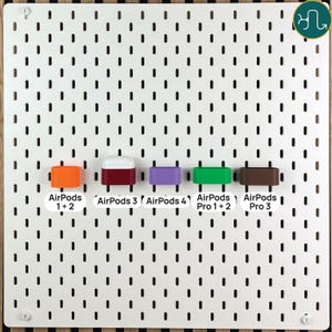 May include: A white pegboard display featuring five colorful silicone holders for wireless earbuds. The labels identify compatibility for AirPods 1+2, AirPods 3, AirPods 4, AirPods Pro 1+2, and AirPods Pro 3. The holders are orange, maroon, purple, green, and brown.
