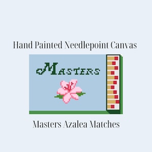 May include: Hand-painted needlepoint canvas featuring a pixelated design. The design includes the word "Masters" in green, a pink azalea flower, and a matchbox-style graphic. The text "Masters Azalea Matches" is below the design.