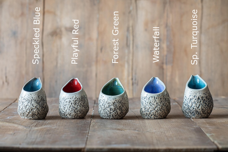Puede incluir: Cinco peque&ntilde;as jarras de cer&aacute;mica con esmalte moteado en varios colores: azul moteado, rojo alegre, verde bosque, cascada y turquesa moteado.