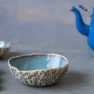 May include: Two blue and white ceramic bowls with a textured exterior. The bowls are on a gray surface.