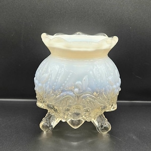 以下が含まれることがあります： スカラップの縁と3つの足が付いた、透明なアンティークガラスボウル。ボウルは薄い青色で、花柄とビーズ模様で装飾されています。ベースと足は透明なガラスです。