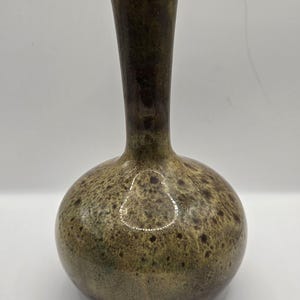 May include: A small, round, brown and green ceramic vase with a speckled glaze.