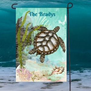 May include: A garden flag with a watercolor design of a sea turtle swimming in the ocean. The flag has the text "The Bradys" printed on it.