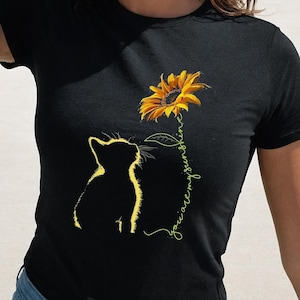 May include: A black t-shirt with a yellow sunflower and a black cat silhouette. The text "You are my sunshine" is written vertically next to the sunflower.