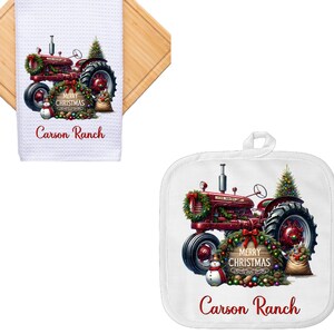 May include: White kitchen towel and pot holder set featuring a red tractor decorated for Christmas. The tractor has a wreath, a Christmas tree, and a snowman. The text "Merry Christmas" and "Carson Ranch" are also visible.