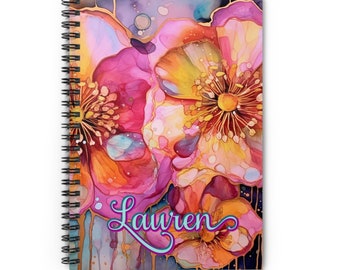 May include: A spiral bound notebook with a watercolor floral design. The flowers are pink, yellow, and orange with gold accents. The name "Lauren" is written in a cursive font on the cover.