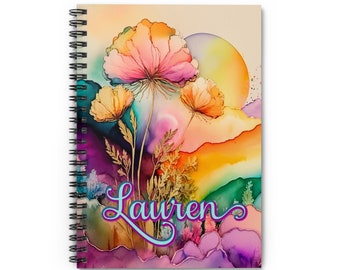 May include: Spiral-bound notebook featuring a watercolor floral design in shades of pink, orange, yellow, and purple. The word "Lauren" is written in a cursive font across the front. The notebook has a black spiral binding.
