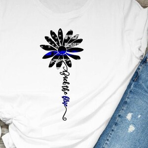 May include: White t-shirt with a blue line American flag daisy design and the text "Back the Blue".