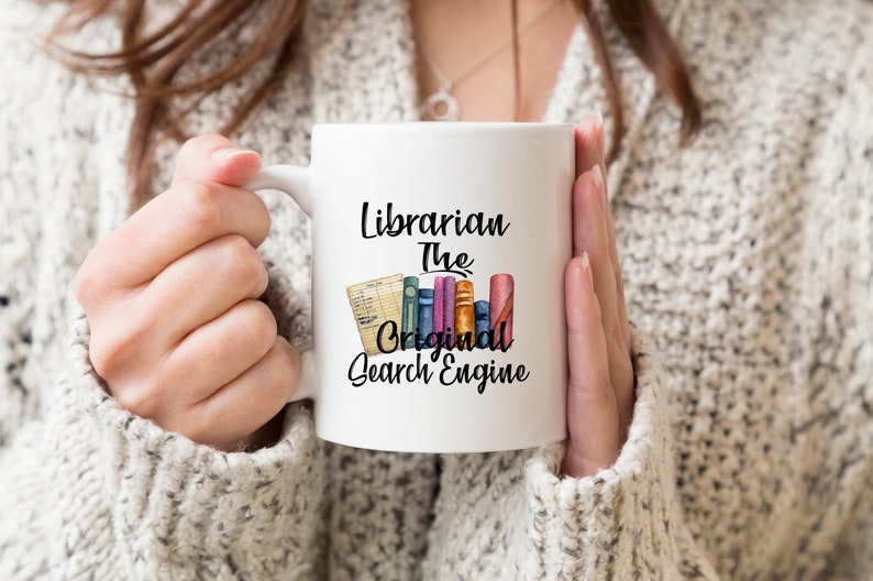 May include: White ceramic mug with a black design that reads "Librarian The Original Search Engine". The design also includes a stack of colorful books and a card with writing on it.
