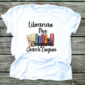 May include: White t-shirt with the text "Librarian The Original Search Engine" in black. The text is accompanied by a watercolor illustration of a stack of books.