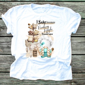May include: White t-shirt with a baking-themed graphic. The design features a gnome chef, baking tools, and the text "I Bake because punching people is frowned upon. Baking is my therapy."