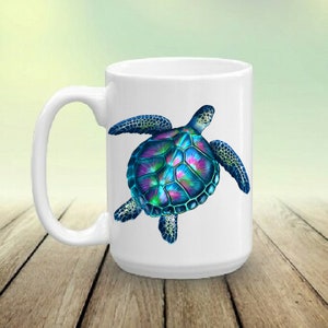 May include: White ceramic coffee mug featuring a colourful sea turtle design. The turtle has a blue, green and purple shell with black outlines.