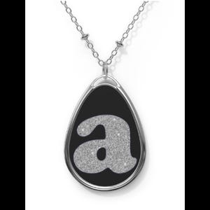 May include: A silver chain necklace with a black teardrop-shaped pendant featuring a silver glitter letter 'a'.
