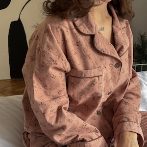 May include: A pink pajama set with a floral print. The top has a collared neckline and long sleeves. The pants have a relaxed fit.