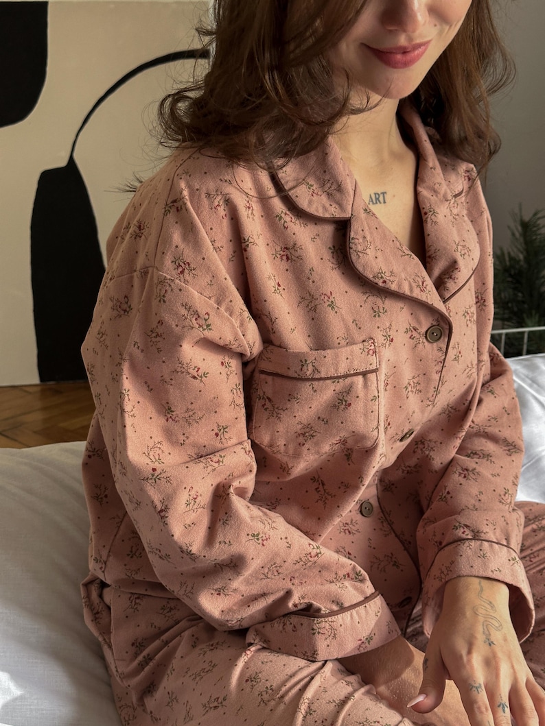 May include: A pink pajama set with a floral print. The top has a collared neckline and long sleeves. The pants have a relaxed fit.