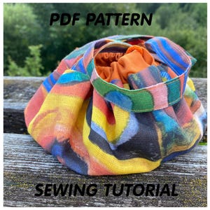 May include: A colorful drawstring bag with a geometric pattern in shades of yellow, orange, blue, green, and black. The bag is made of fabric and has a drawstring closure. The text "PDF PATTERN" and "SEWING TUTORIAL" is visible on the image.
