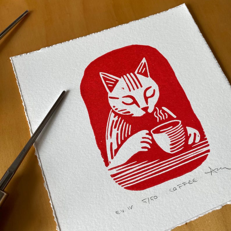 Cat drinking a cup of coffee, red ink print. Katze trinkend eine Tasse Kaffee, roter Tintendruck. Chat buvant une tasse de café, estampe à l'encre rouge. Gatto che beve una tazza di caffè, stampa a inchiostro rosso. Gato tomando una taza de café, grabado en tinta roja. Linocut, linoprint, lino cut, linogravure, relief print. Linolschnitt, Linodruck, Linogravur, Hochdruck. Linogravure, gravure sur linoléum, estampage en relief. Linoleografia, stampa su linoleum,  Linóleo, linograbado